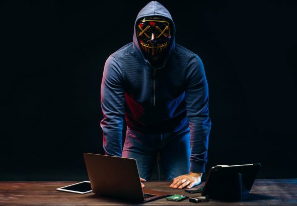 anonymous hacker man isolated over dark space